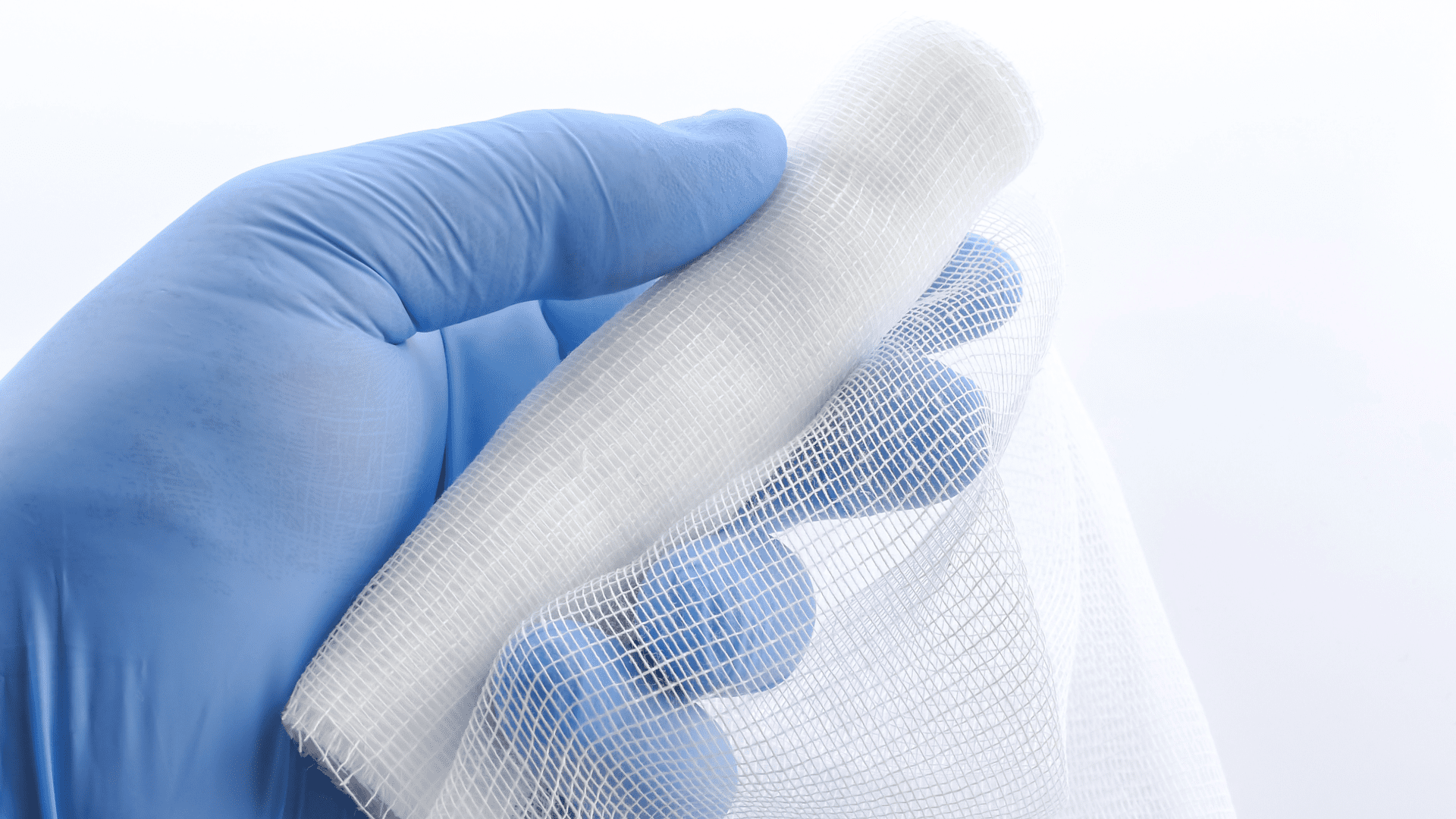 Hand in glove holding sterile gauze pad for wound care